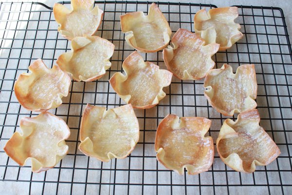 Baked wontons on top of a wire cookie rack.