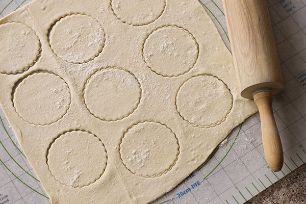 pastry dough on a pastry mat with cutouts and a rolling pin on the side